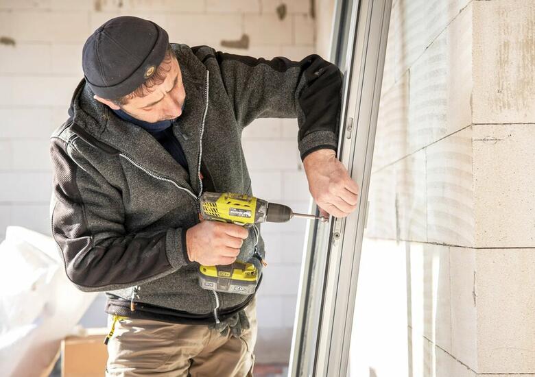 Montér připravuje nová okna na instalaci