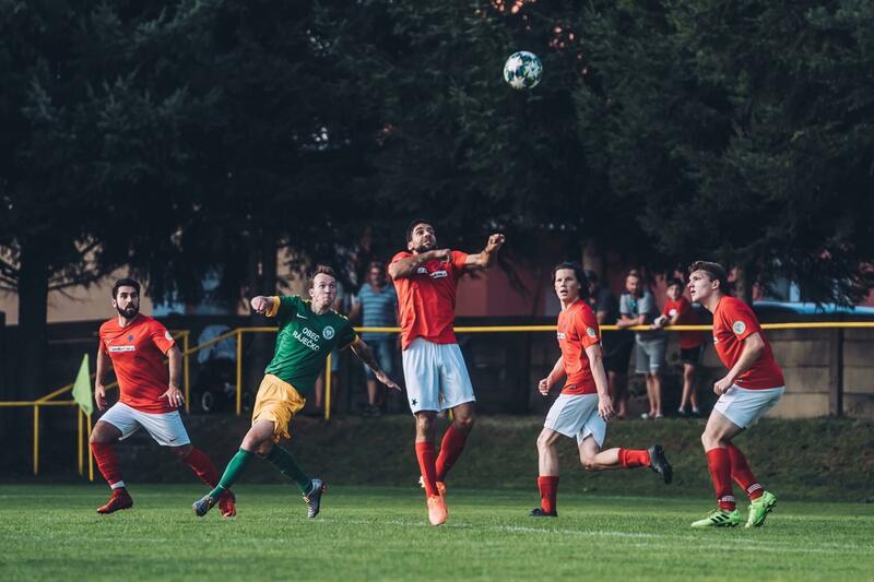 Skupina fotbalistů v červenobílých dresech hraje fotbal